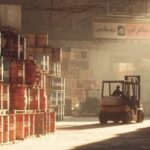 انبار بزرگ پخش عمده روغن موتور در فارس؛ چیدمان بشکه‌ها و کارگر در حال جابه‌جایی محموله با لیفتراک در محیطی صنعتی و خاکی